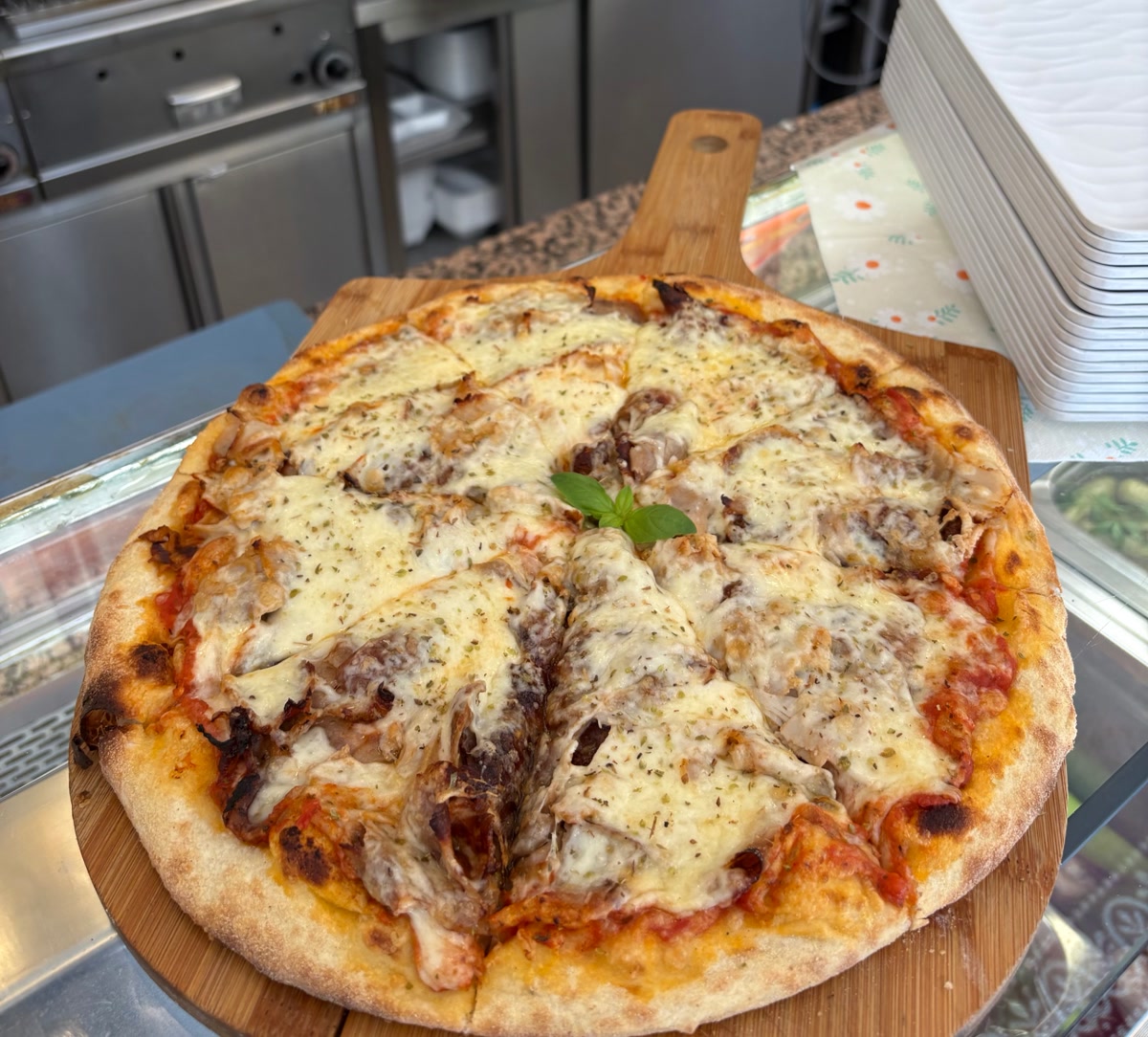 Mitarbeiter präsentiert zwei frisch gebackene Pizzen auf Holzbrettern