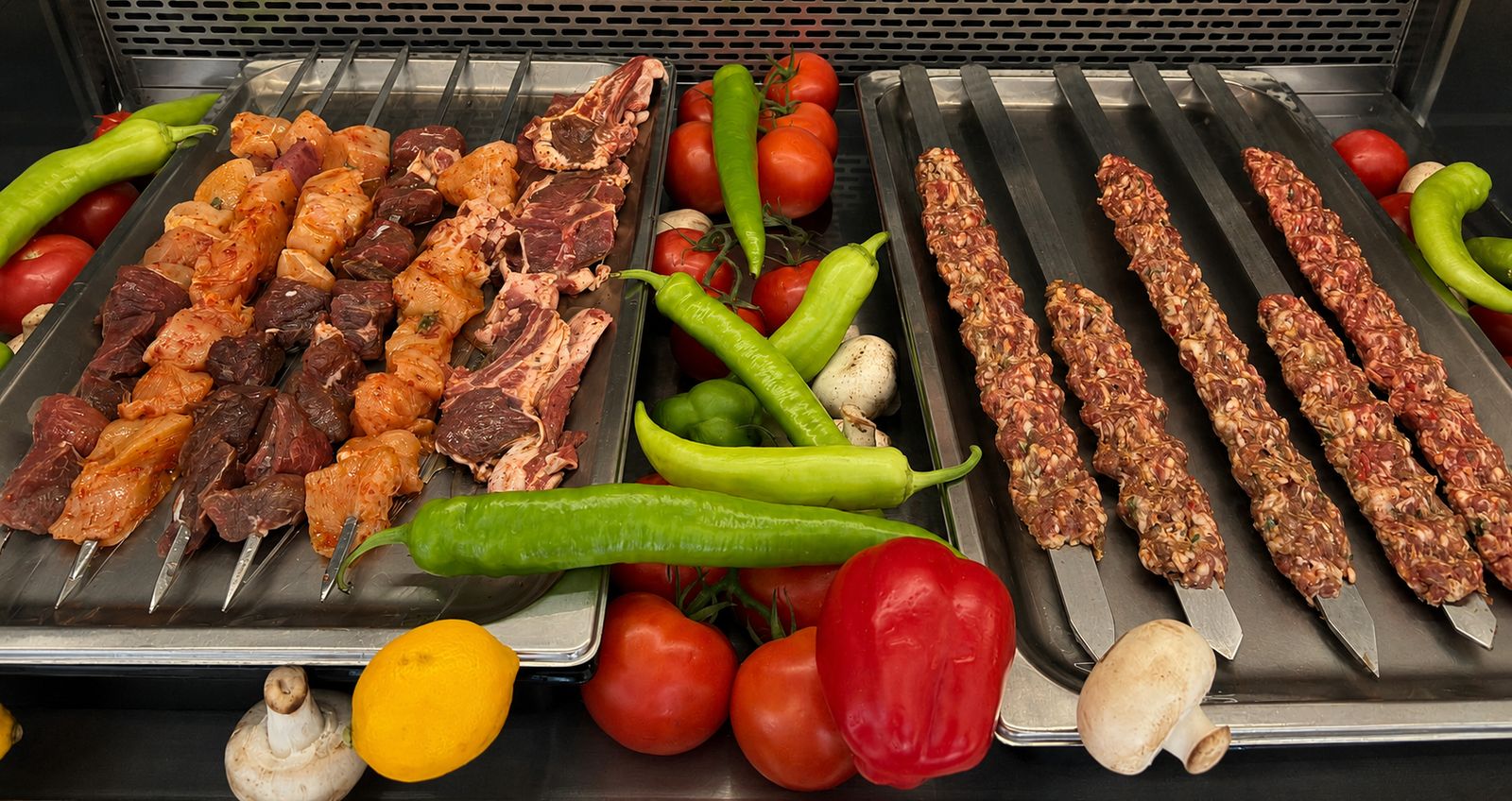 Vorbereitete Fleischspieße und Adana-Spieße mit frischem Gemüse in der Kühltheke